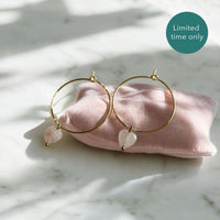 Earrings with a 8mm faceted heart Rose Quartz bead on a 30mm diameter fine gold plated hoop on a pink velvet pillow.