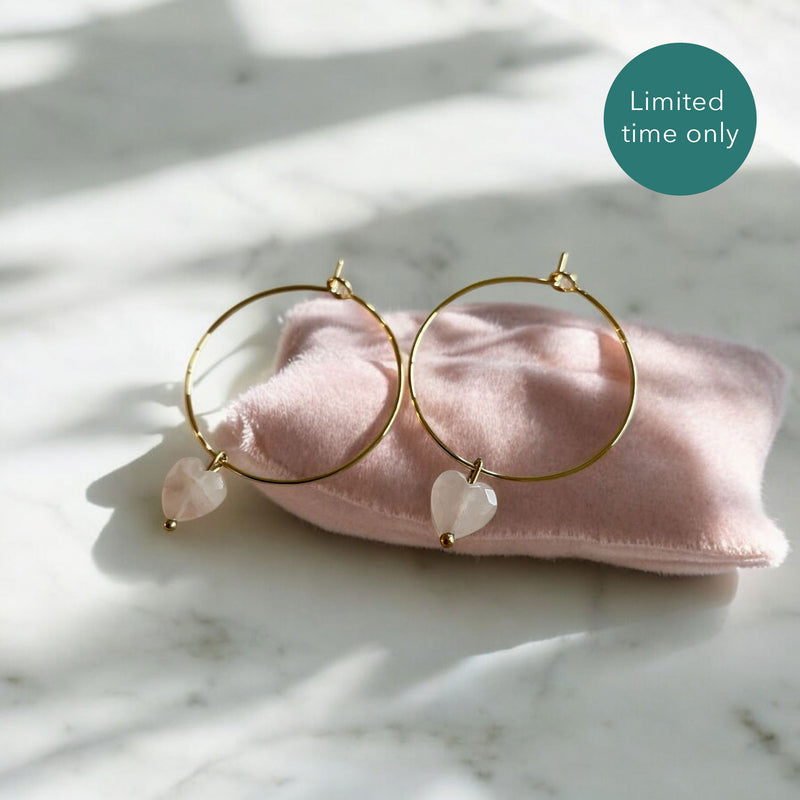 Earrings with a 8mm faceted heart Rose Quartz bead on a 30mm diameter fine gold plated hoop on a pink velvet pillow.
