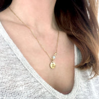 Woman wears a fine golden necklace with a gemini pendant, a Citrine and a Aquamarine bead.