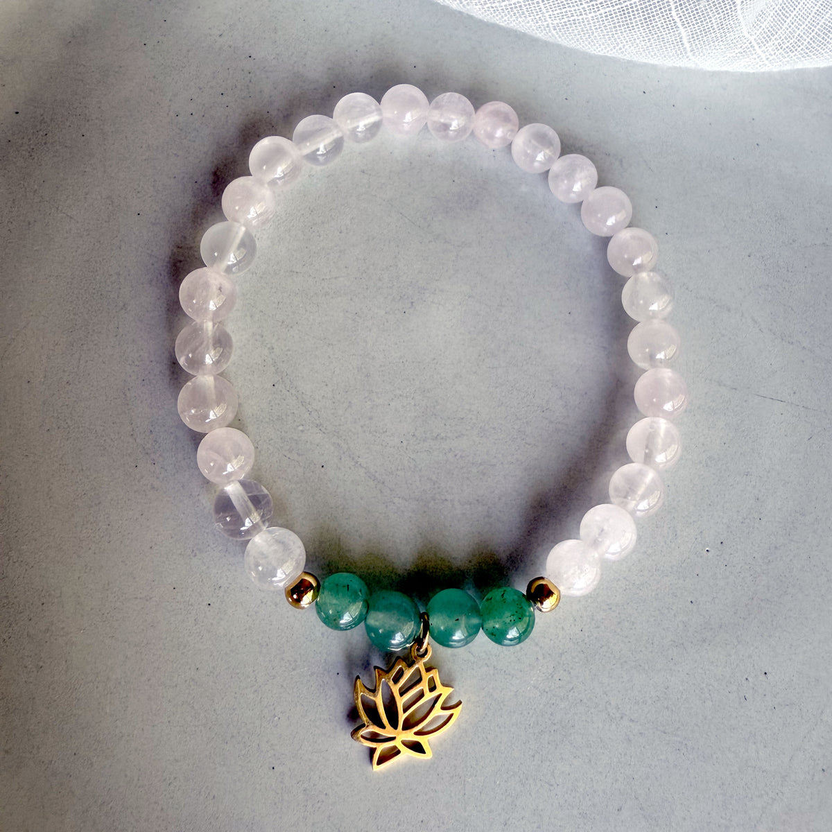“I Am Love” chakra bracelet by Moksha Jewelry, made with rose quartz and green aventurine beads, gold-plated accents, and a lotus charm, styled on a soft gray background—designed to open the heart chakra and promote love, harmony, and emotional healing.