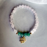 “I Am Love” chakra bracelet by Moksha Jewelry, made with rose quartz and green aventurine beads, gold-plated accents, and a lotus charm, styled on a soft gray background—designed to open the heart chakra and promote love, harmony, and emotional healing.