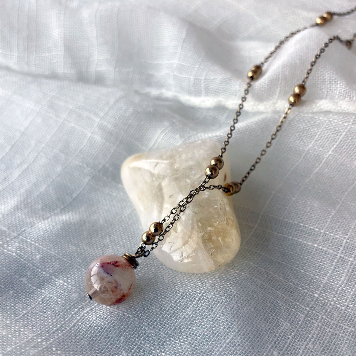 A close-up of a gold plated necklace with a 10mm Citrine bead on a delicate chain with 3mm Ball and 1mm Curb Chain.