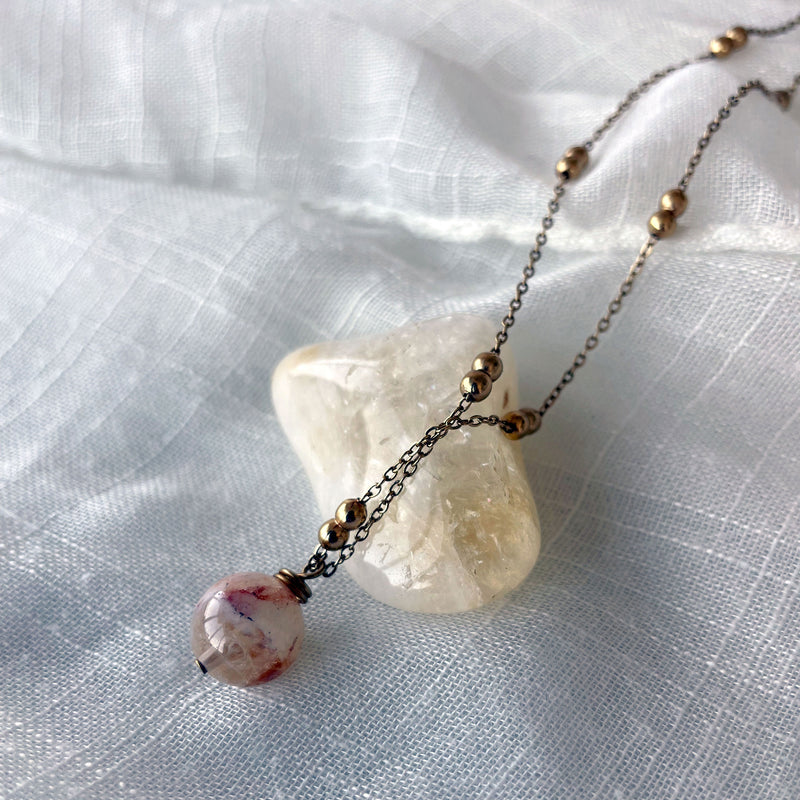 A close-up of a gold plated necklace with a 10mm Citrine bead on a delicate chain with 3mm Ball and 1mm Curb Chain.