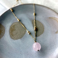 A close-up of a gold plated necklace with a 10mm Rose Quartz bead on a delicate chain with 3mm Ball and 1mm Curb Chain.