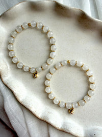 Two handcrafted Lunar Moonstone Bracelets with genuine Moonstone gemstones, gold-plated spacer beads, and crescent moon charms displayed on a ceramic tray.