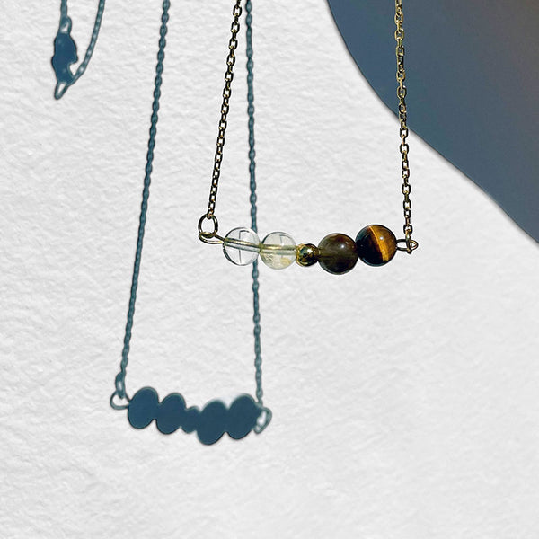 A fine golden necklace with 2 citrine beads, 2 tiger eye beads and one golden bead in the middle.