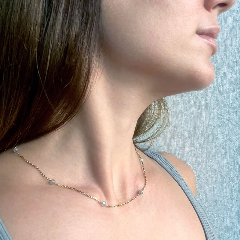 A woman wears a fine golden necklace with 4mm Labradorite beads.