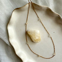 A delicate gold-plated chain with six small 4mm citrine beads, displayed on a ceramic dish, symbolizing abundance and positivity.