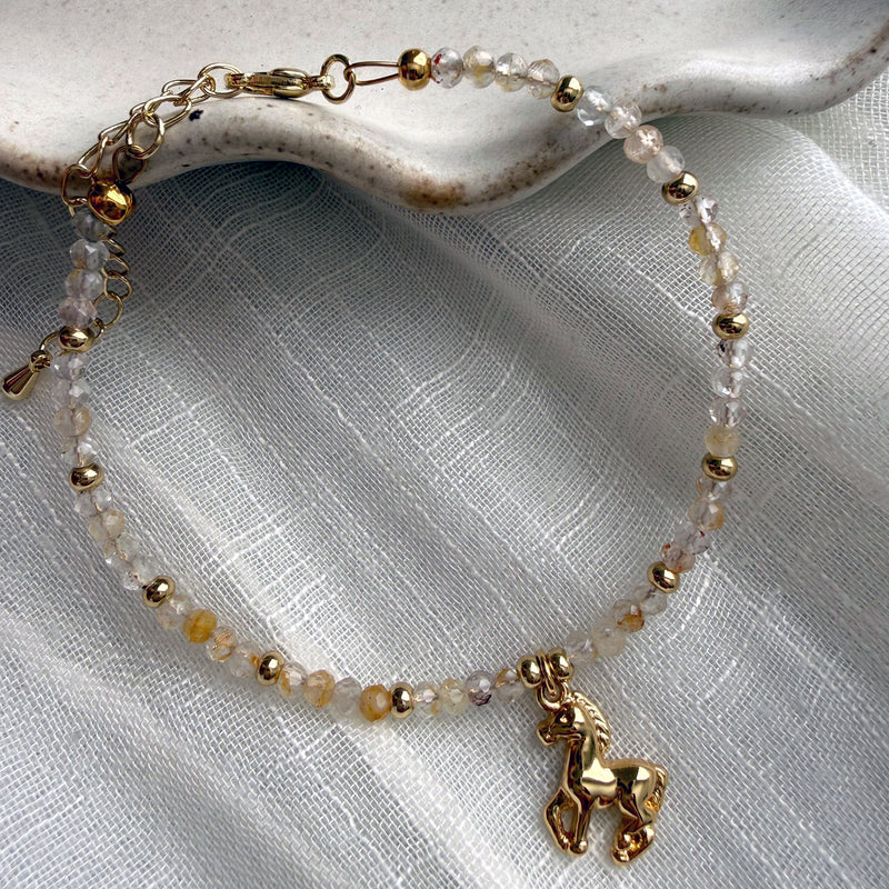 Handmade gold horse charm bracelet with faceted topaz gemstone beads and gold-filled details on white fabric – Year of the Horse jewelry by Moksha Jewelry.
