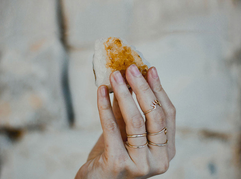 A close-up of a hand holds a raw citrine gemstone.