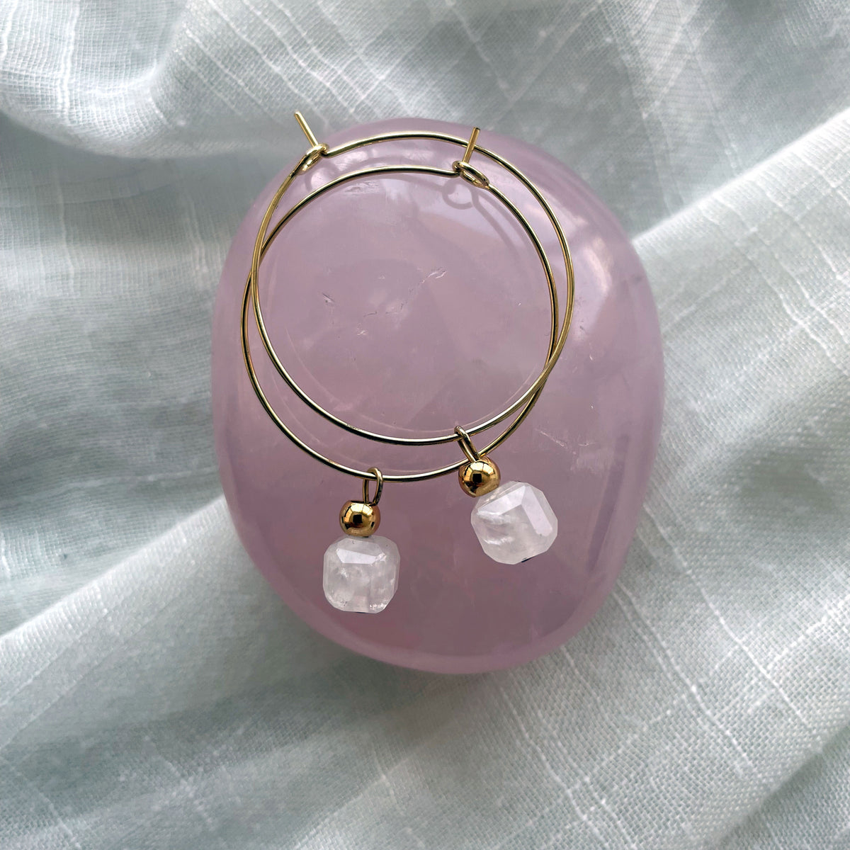 Earrings with a 7mm faceted Rose Quartz cube bead and a 4mm gold plated bead on a 30mm diameter fine gold plated hoop on a rose quartz gemstone.